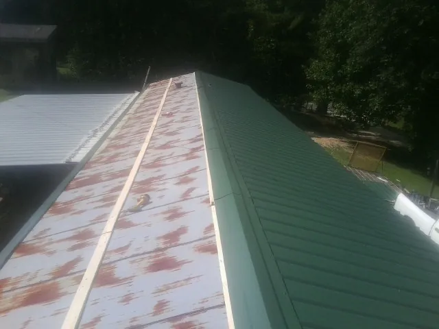 Old rusted panels beside newly installed green metal roofing — Wind Damage Roof Repair by Roofing Brothers in Rockvale