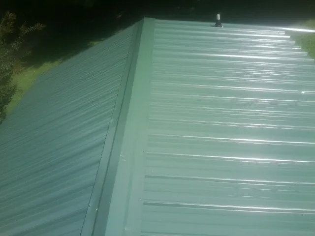 New green metal panels meeting at the ridge of a roof — Flat Roof Repair work by our crew in Rockvale